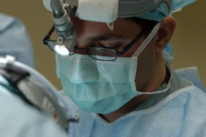 Cirurgião oftalmológico realizando procedimento com lupa, representando uma cirurgia para ceratocone.